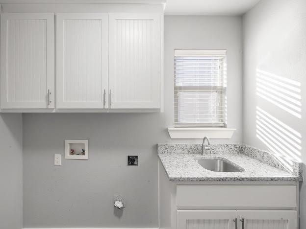 clothes washing area with electric dryer hookup, sink, hookup for a washing machine, and cabinets