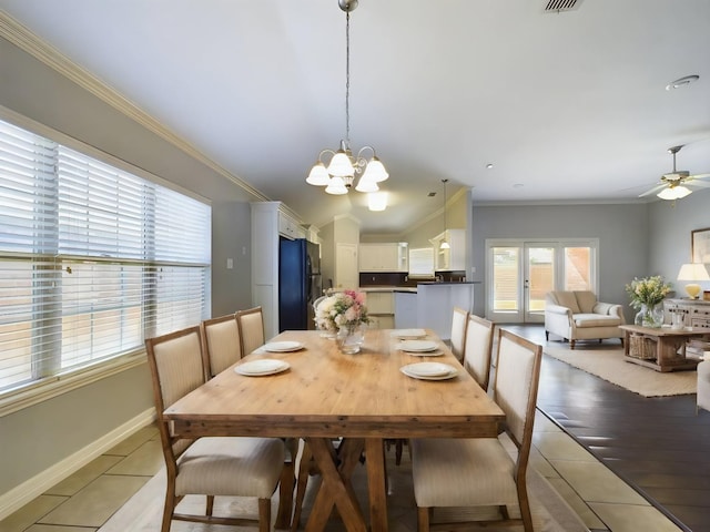 dining space featuring french doors, ornamental molding, ceiling fan with notable chandelier, and light hardwood / wood-style flooring