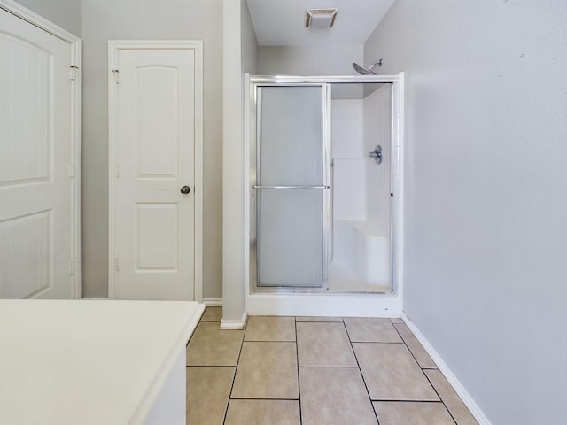 bathroom with a shower with door and tile patterned floors