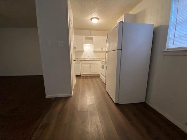 kitchen featuring dark hardwood / wood-style flooring, a textured ceiling, white cabinets, and white appliances