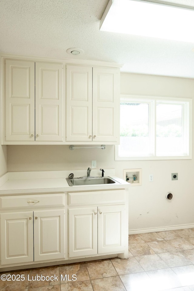 4420 87th St, Lubbock, TX 79424 - clothes washing area featuring washer hookup, cabinet space, electric dryer hookup, light tile patterned floors, and baseboards
