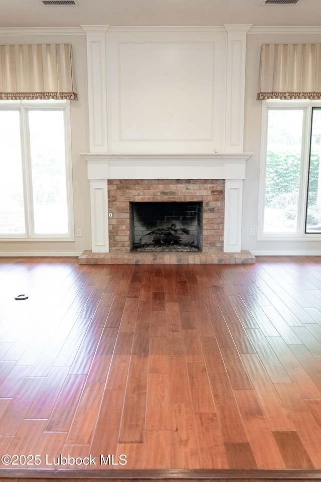4420 87th St, Lubbock, TX 79424 - unfurnished living room with a fireplace with raised hearth, light wood-style floors, and crown molding