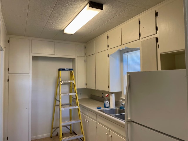 kitchen with white cabinetry, sink, and white refrigerator