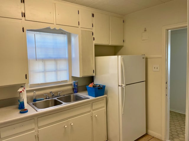 kitchen with white refrigerator, sink, and white cabinets