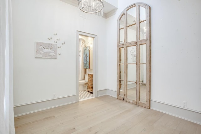 empty room featuring a notable chandelier and light wood-type flooring