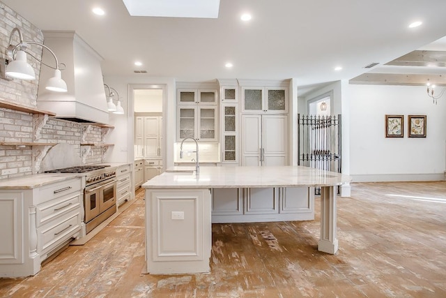 kitchen featuring hanging light fixtures, white cabinetry, a breakfast bar, and a center island with sink