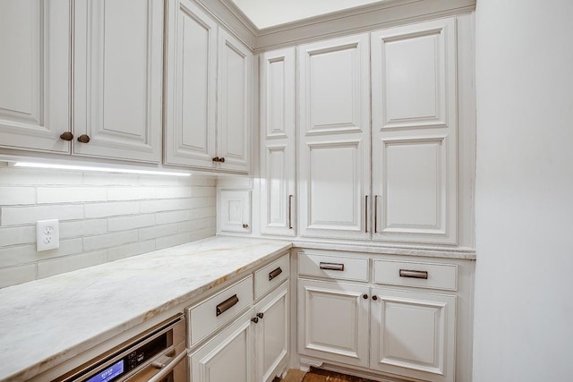 kitchen with light stone counters, white cabinetry, and decorative backsplash