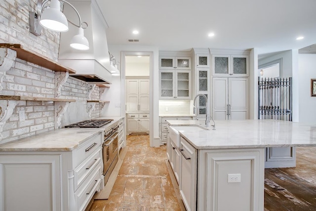 kitchen featuring sink, a center island with sink, white cabinets, and decorative light fixtures