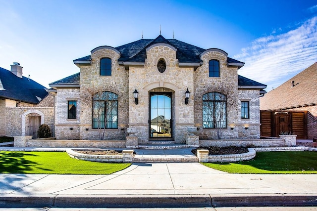 french country inspired facade featuring a front yard