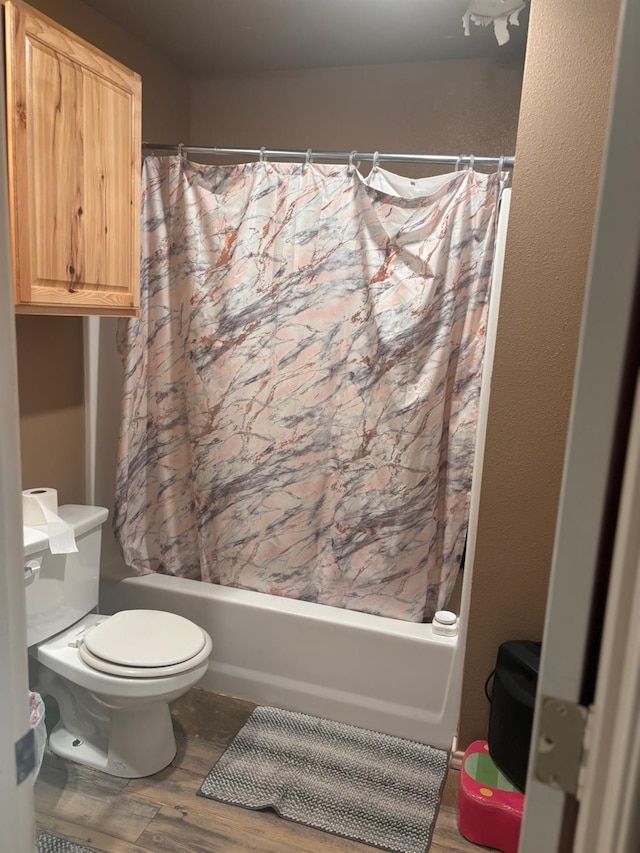 bathroom with shower / bath combination with curtain, wood-type flooring, and toilet