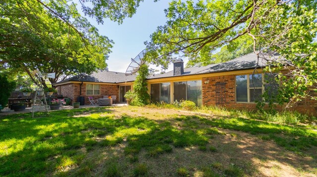 rear view of property featuring a patio area and a lawn