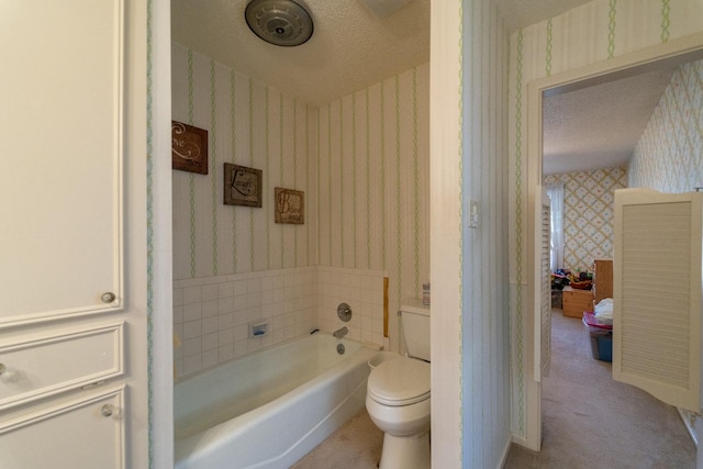 bathroom featuring toilet, a textured ceiling, and a tub to relax in