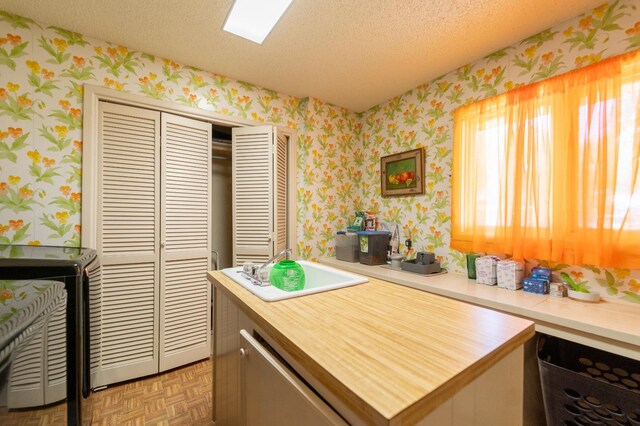 kitchen with light parquet floors, dishwasher, and a textured ceiling