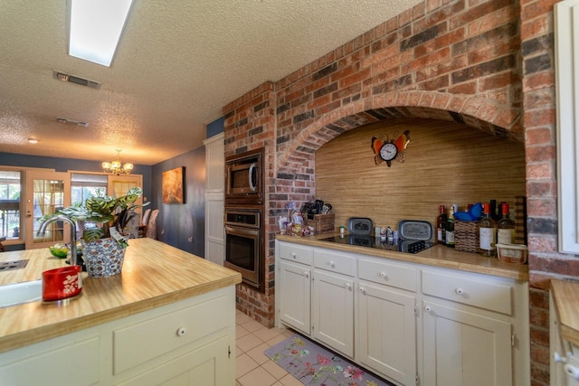 kitchen featuring sink, white cabinets, stainless steel appliances, a textured ceiling, and an inviting chandelier