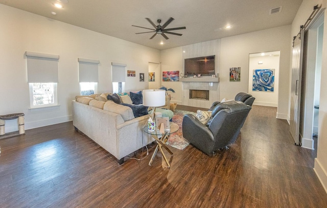 living room featuring dark hardwood / wood-style floors, a barn door, and ceiling fan