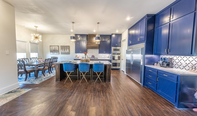 kitchen featuring built in appliances, a kitchen breakfast bar, blue cabinets, pendant lighting, and a kitchen island