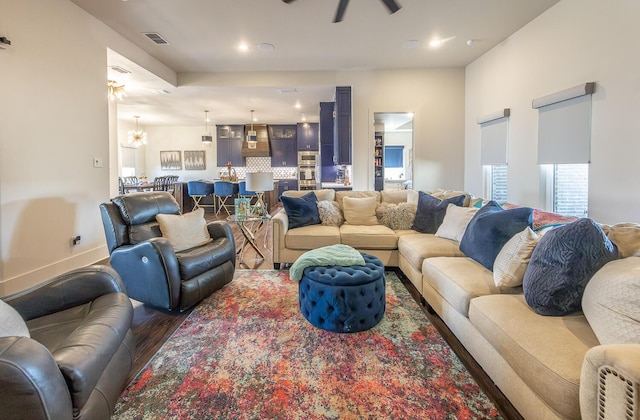 living room featuring dark wood-type flooring and ceiling fan with notable chandelier