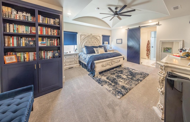 carpeted bedroom featuring a barn door and a raised ceiling