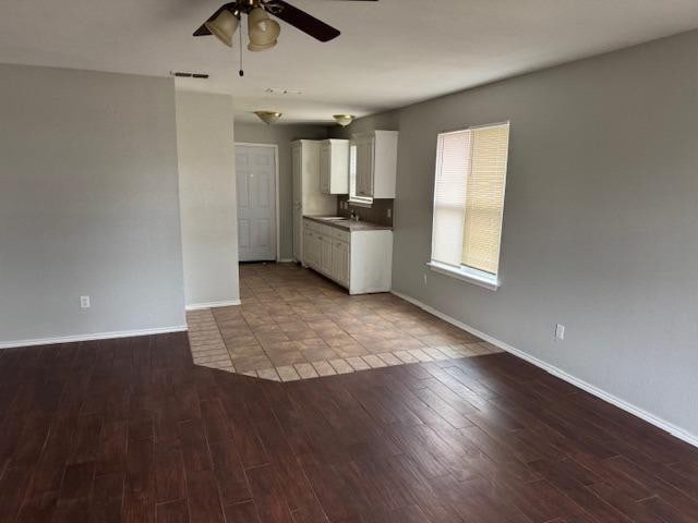 unfurnished living room with wood-type flooring, sink, and ceiling fan