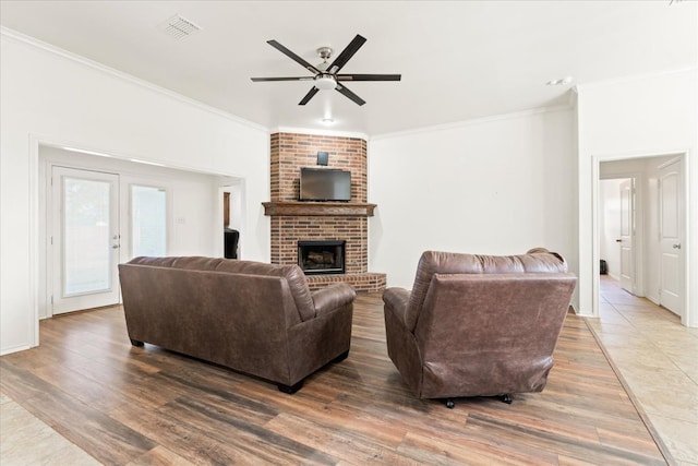 living room featuring crown molding, ceiling fan, wood-type flooring, and a fireplace