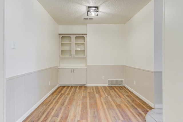 empty room with light hardwood / wood-style flooring and a textured ceiling