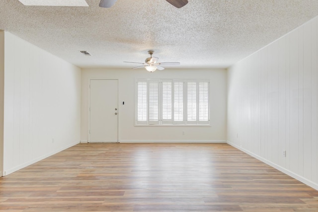 spare room featuring a textured ceiling, ceiling fan, and light hardwood / wood-style flooring