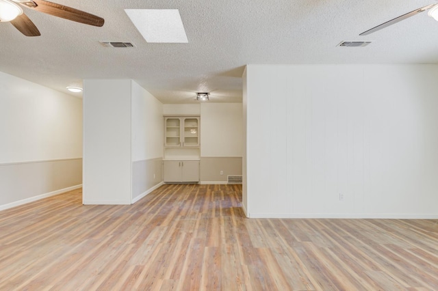 empty room with ceiling fan, light hardwood / wood-style flooring, and a textured ceiling