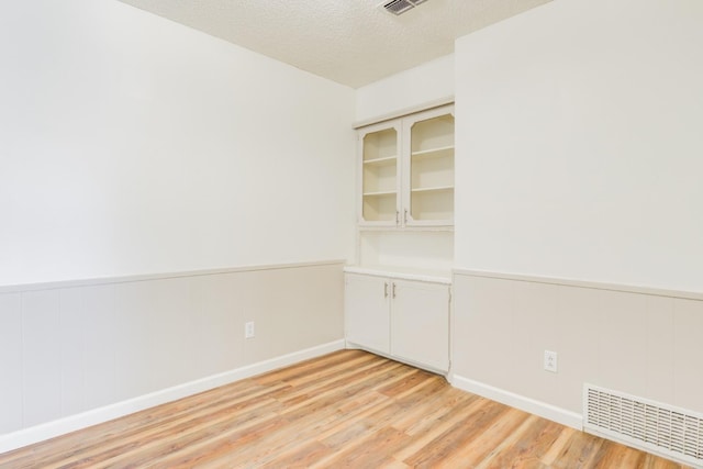 unfurnished room featuring a textured ceiling and light hardwood / wood-style floors