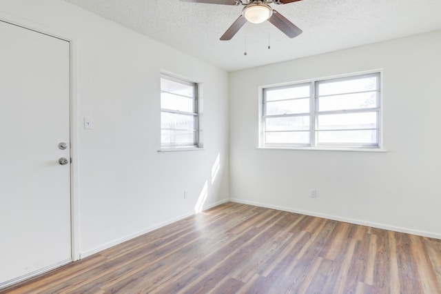 unfurnished room with ceiling fan, dark wood-type flooring, and a textured ceiling