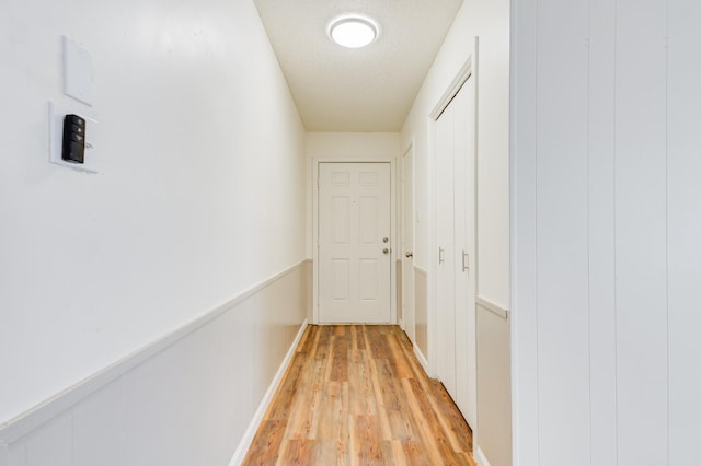 hall with a textured ceiling and light hardwood / wood-style floors