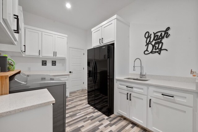 kitchen with white cabinets, black refrigerator, sink, and washing machine and clothes dryer