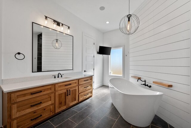 bathroom with a bathing tub, vanity, and tile patterned floors