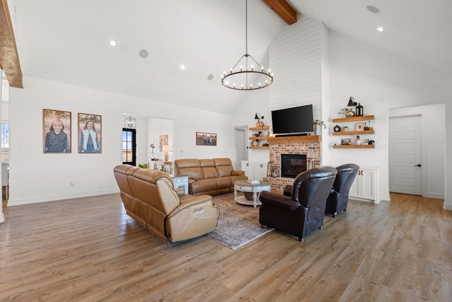 living room featuring beamed ceiling, a wealth of natural light, a fireplace, and light hardwood / wood-style flooring