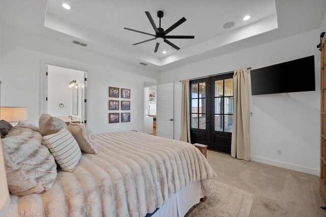 bedroom featuring access to exterior, a tray ceiling, a barn door, light colored carpet, and french doors