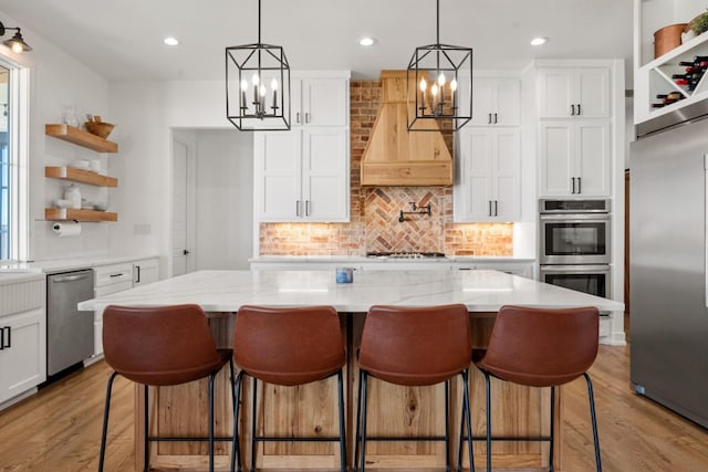 kitchen with white cabinetry, custom exhaust hood, a center island, and appliances with stainless steel finishes