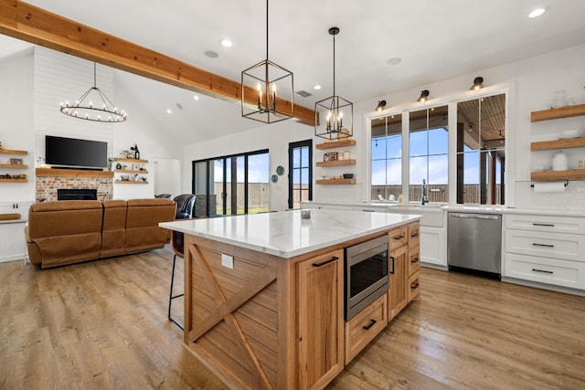 kitchen with a center island, hanging light fixtures, stainless steel appliances, light stone countertops, and white cabinets