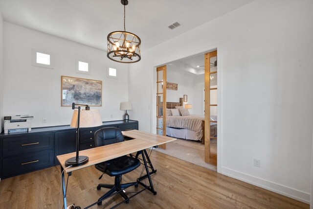 office with light hardwood / wood-style flooring, french doors, and a chandelier