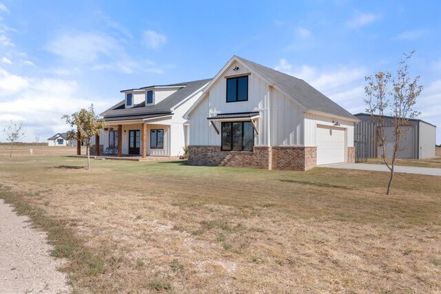 modern inspired farmhouse featuring a garage, a porch, and a front lawn