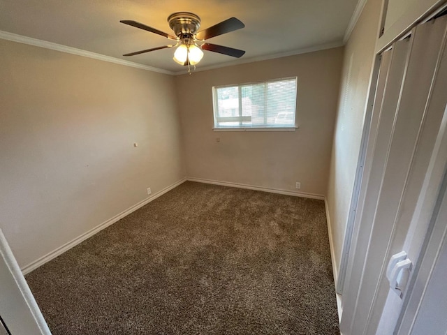 spare room with dark colored carpet, ceiling fan, and crown molding