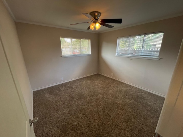 spare room with ceiling fan, ornamental molding, and dark colored carpet