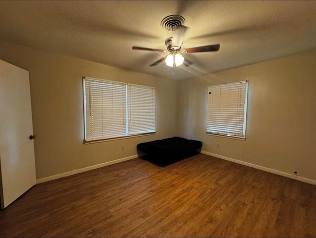 unfurnished room with ceiling fan, dark hardwood / wood-style flooring, and a textured ceiling