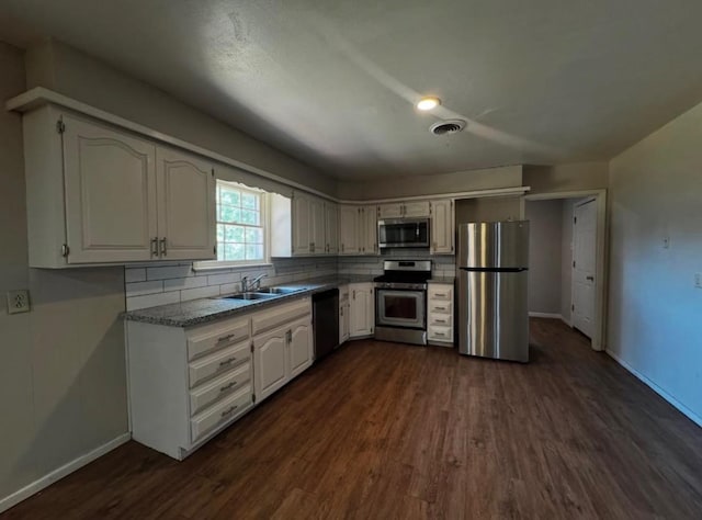 kitchen with white cabinetry, appliances with stainless steel finishes, dark wood-type flooring, and backsplash