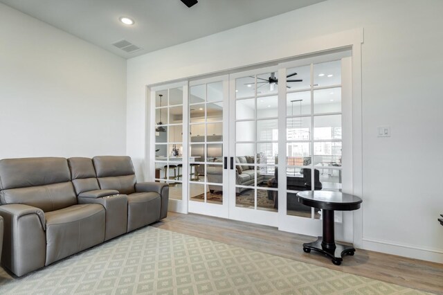 living room featuring french doors, ceiling fan, and light wood-type flooring