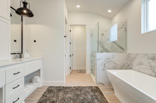 bathroom featuring hardwood / wood-style flooring, shower with separate bathtub, vaulted ceiling, and vanity