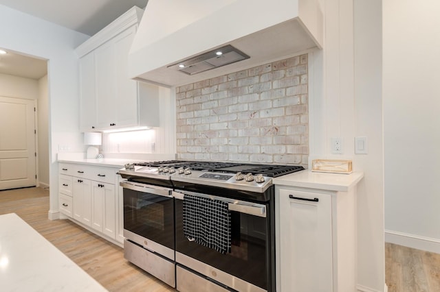 kitchen featuring white cabinetry, decorative backsplash, custom exhaust hood, light hardwood / wood-style floors, and gas stove