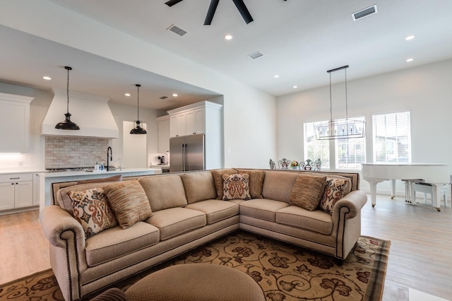 living room featuring ceiling fan, sink, and light hardwood / wood-style floors