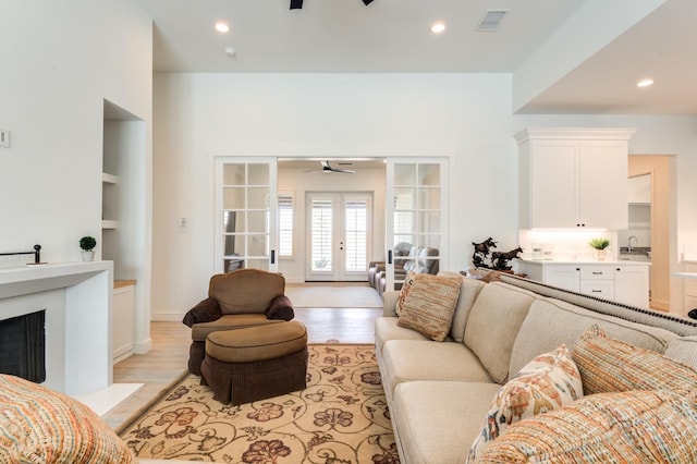 living room with light hardwood / wood-style floors, sink, ceiling fan, and french doors