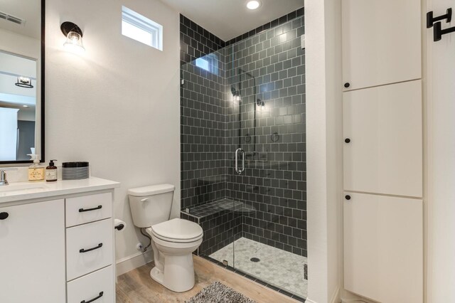 bathroom with walk in shower, vanity, toilet, and hardwood / wood-style flooring