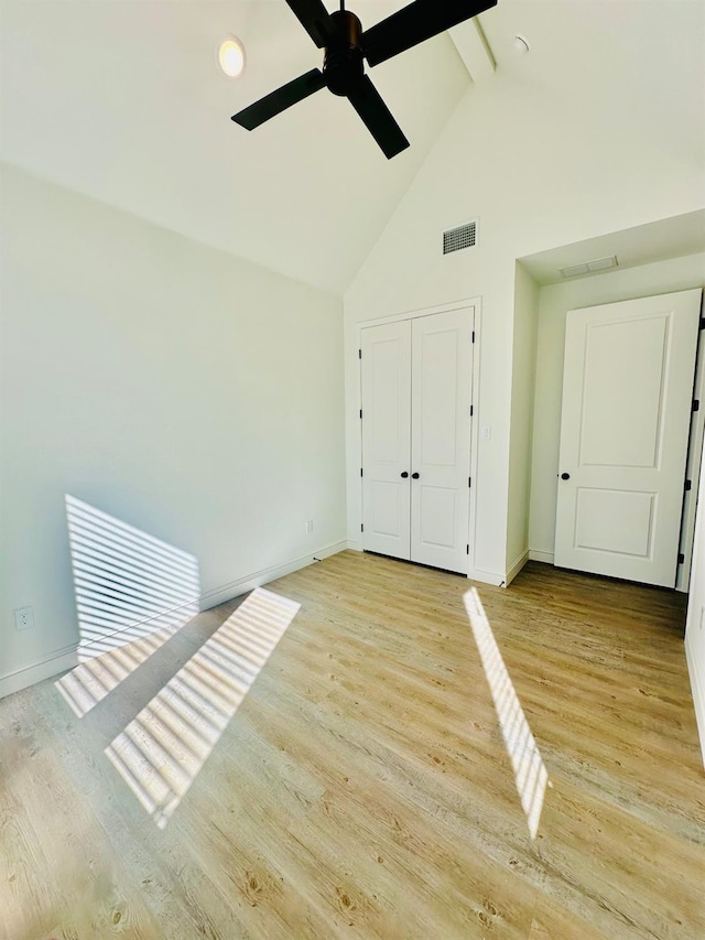 unfurnished bedroom featuring beamed ceiling, high vaulted ceiling, light hardwood / wood-style floors, and a closet