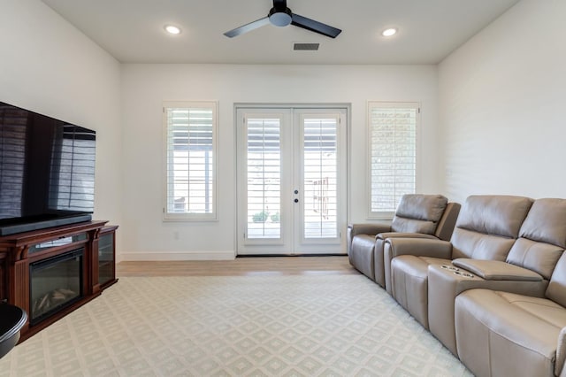 living room with light hardwood / wood-style flooring, ceiling fan, and french doors